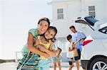 Mother and daughter hugging outside beach house