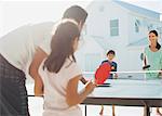 Family playing table tennis outside house