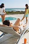 Mother and daughters relaxing at poolside