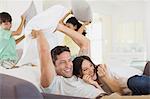 Family enjoying pillow fight in living room