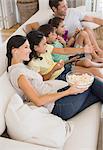 Family watching movie on sofa in living room