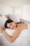 Woman hugging pillow on bed