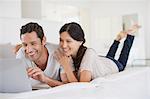 Couple using laptop on bed