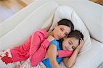 Mother and daughter napping on sofa in living room