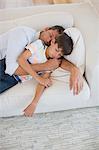 Father and son napping on sofa in living room