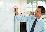 Businessman writing on whiteboard in office