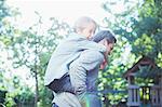 Father carrying son piggyback outdoors