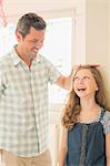 Father measuring daughter's height on wall