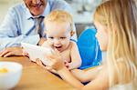 Girl showing baby digital tablet at table