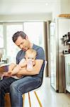 Father feeding baby in kitchen