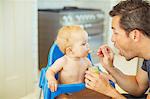 Father feeding baby in high chair