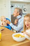 Father and children eating breakfast in kitchen