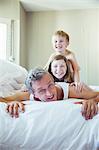 Father and children playing on bed