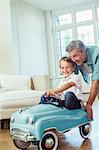 Father pushing son in toy car