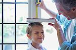 Father measuring son's height on wall