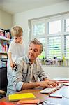 Boy distracting father at work in home office