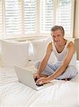 Man using laptop on bed