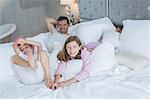 Father and children relaxing on bed