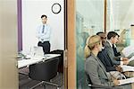 Businessman standing in office and business people in corridor