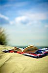 Open book on towel at sandy beach