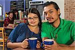 Grinning Latino and Asian couple in cafe