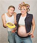 Angry pregnant woman in curlers with candy and man