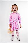 Full length portrait of a little 2 years old girl standing with handbag over white background