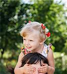 little girl hiding her mother face with palms outdoors