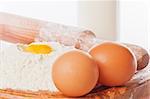 Vintage rolling pin with flour and eggs. Country still life images with soft lighting and small degrees of freedom (selective focus on the yolk)