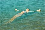 Teen girl lying on the turquoise sea water surface in shallow coastal area