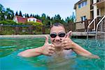 Boy in the pool outdoors showing thumb up