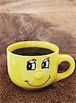 Yellow mug with smile and coffee on the table with a instant coffee granules
