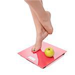 Woman perfect shaped legs on scale with apple on white background