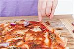 hand of young child making pizzaon wooden board