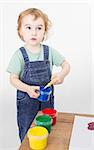 little girl with brush in paint tub. studio shot on light grey background