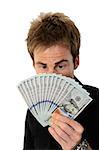 A young handsome man holding a lot of new hundred dollar bills isolated on white background.  He is staring at the money.  This newly redesigned US currency was released for circulation in October of 2013.