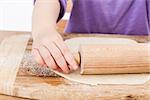 young child rolling out dough for a homemade pie