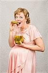 Overjoyed pregnant female eating from a jar of pickles