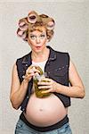 Pregnant white woman in curlers with jar of pickles