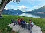 Lake Como evening view (Italy) and family resting on bench