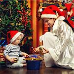 mother and baby sitting next christmas tree