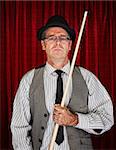 Serious retro style man with pool cue on curtain background