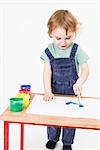 young girl working with paint on wooden desk. Studio shot in light grey background