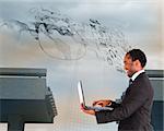 Composite image of smiling businessman working on laptop