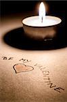 Be my Valentine message and a heart by the candle light.
