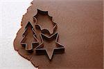 Cutting out Christmas tree, holly leaf and star shapes from gingerbread dough