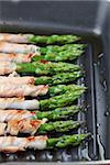 Prosciutto wrapped green asparagus on a grilling pan