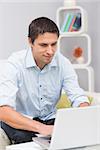 Smiling young man using laptop in living room at home