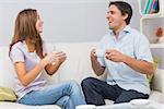 Cheerful young couple sitting on sofa and enjoying their tea at home