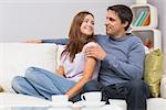 Relaxed loving young couple sitting on sofa and looking at each other at home